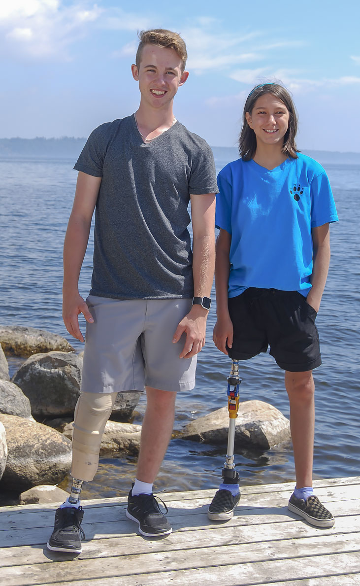 CHAMP Ambassadors Adam and Rebecca, both leg amputees, stand on a dock by a lake.