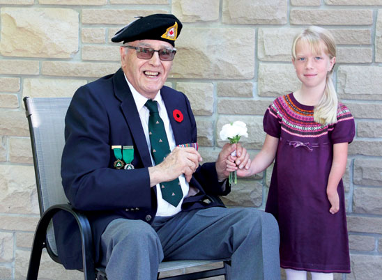 Une jeune fille amputée du bras gauche offre une rose blanche à un ancien combattant de la Deuxième Guerre mondiale portant son uniforme.