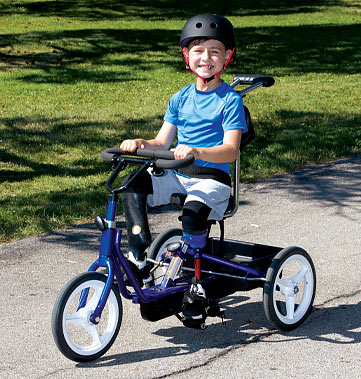 Dylan, a double leg amputee, wearing his artificial legs and riding his adaptive three-wheeled bicycle.