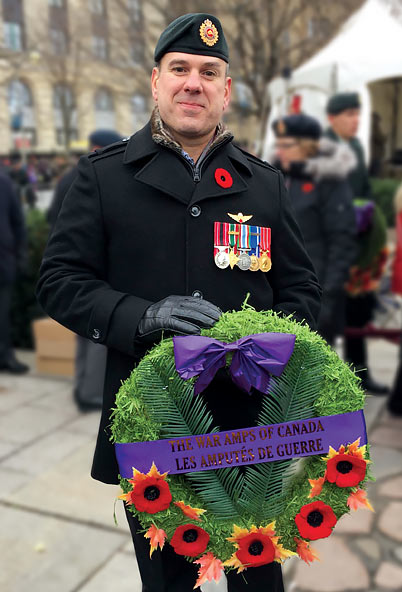 Retired sergeant Gaétan, a leg amputee, holding a wreath at a Remembrance Day ceremony.