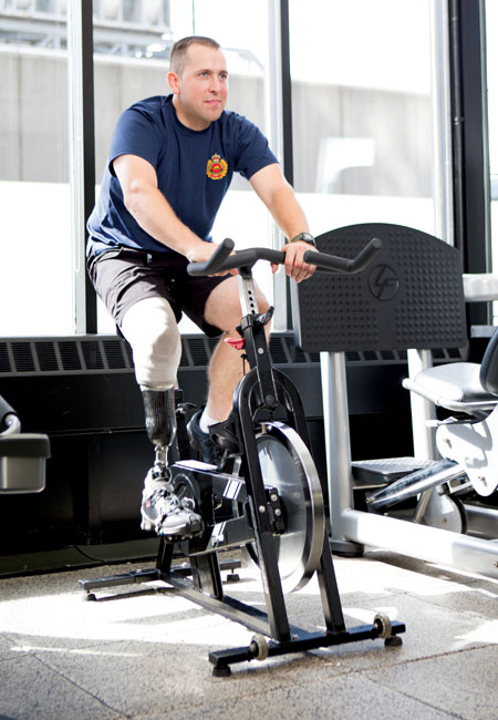 An Afghanistan War leg amputee rides a stationary bike while wearing his artificial leg.