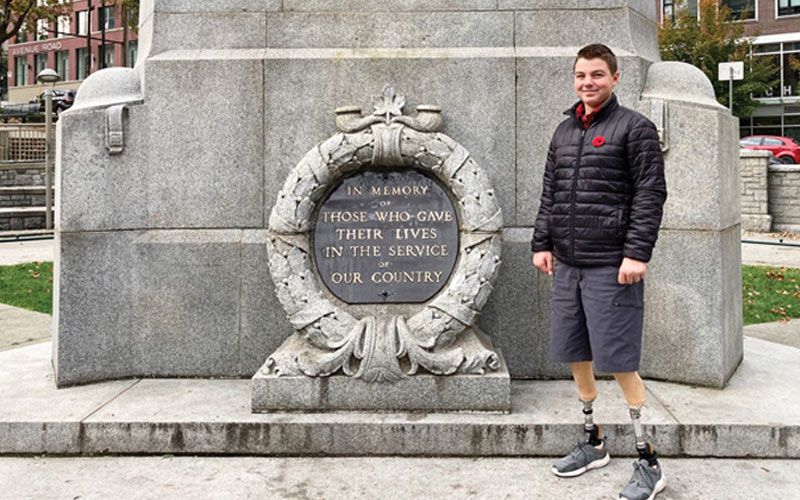 A male amputee stands in front of a cenotaph.