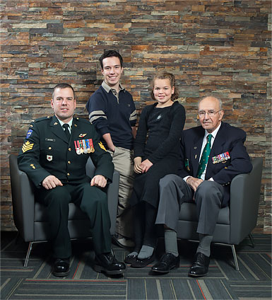 Two war amputee veterans posing with two young child amputees.