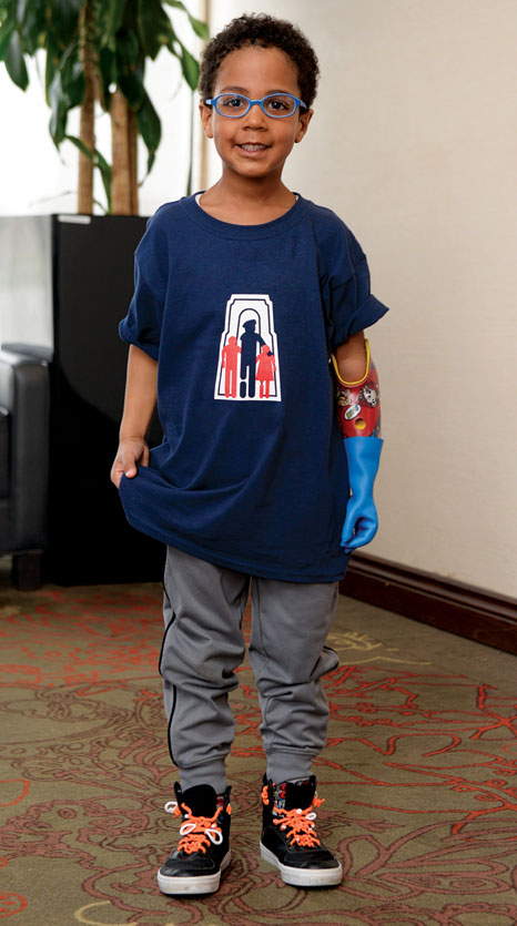 Un garçon amputé d’un bras se tient debout dans le vestibule d’un hôtel.