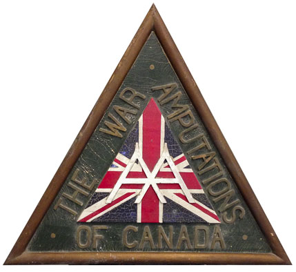 The 1939 War Amps logo crafted onto a triangular wooden plaque.