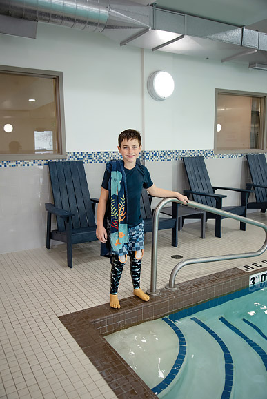 Maddux wearing his water legs and standing beside a pool.