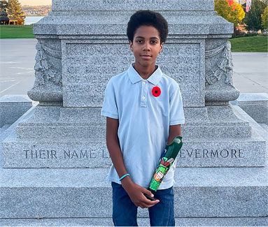 Deji, an arm amputee, standing in front of a monument.