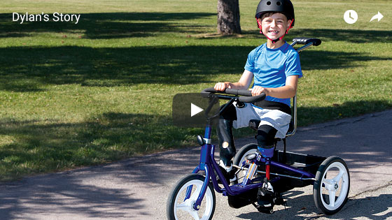 Dylan, a double leg amputee, wearing his artificial legs and riding his adaptive three-wheeled bicycle. Links to a video about Dylan.