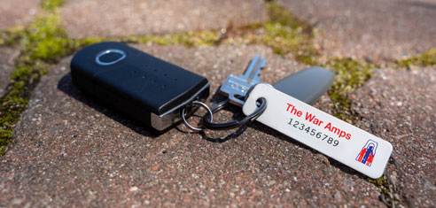 A set of keys with a War Amps key tag attached lying on the ground.