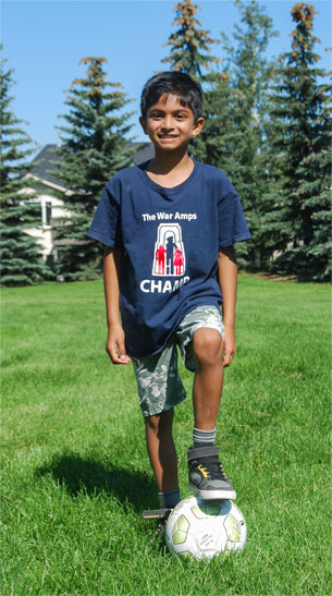 Champ Jordan standing in a field with his foot resting on top of a soccer ball.