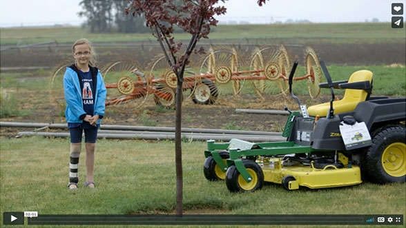 Neveah standing in a field with a lawn mower